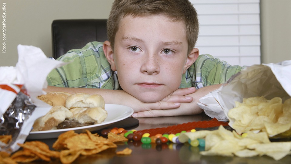 Ein Junge sitzt vor einem Tisch voller Essen
